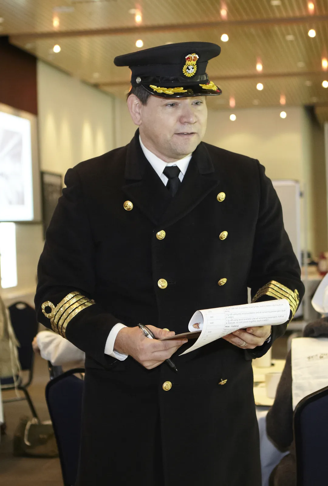 Doug Bolger in full Captain Smith uniform reading from ship's manifest — the facilitator who guides your team through the Save the Titanic experience