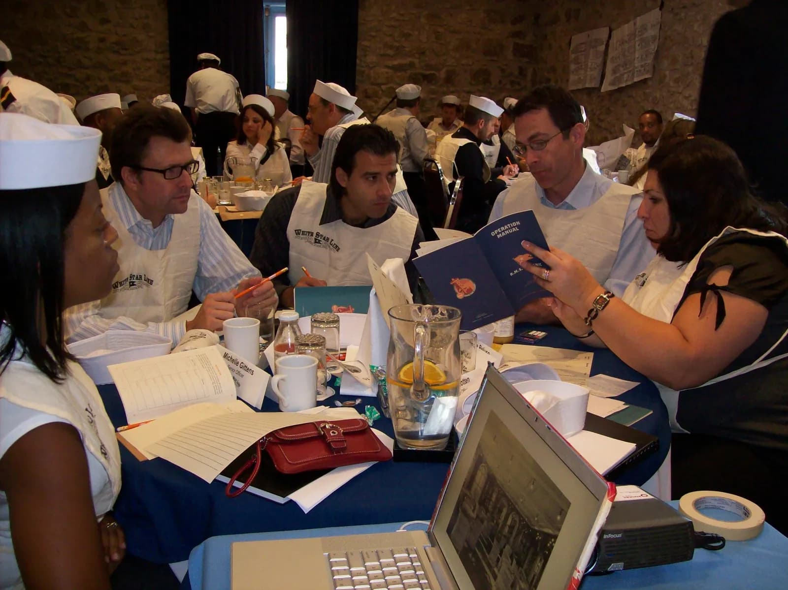 Diverse crew members reading the Operation Manual together at a round table during Save the Titanic — deep collaboration under pressure